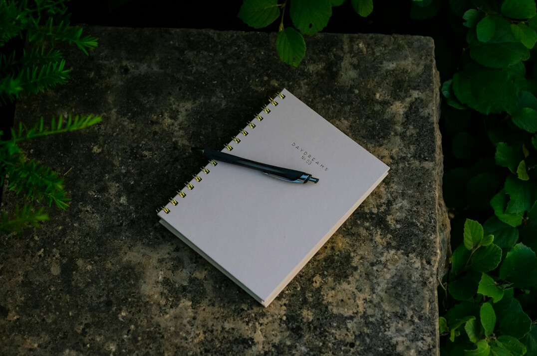 Open journal notebook with a pen on a wooden desk in warm light
